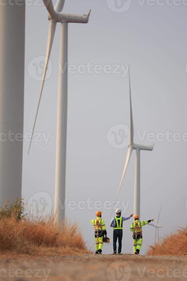 Specialist wind turbine Team of Engineers discussing Green Energy Production in Wind Turbines Farm photo