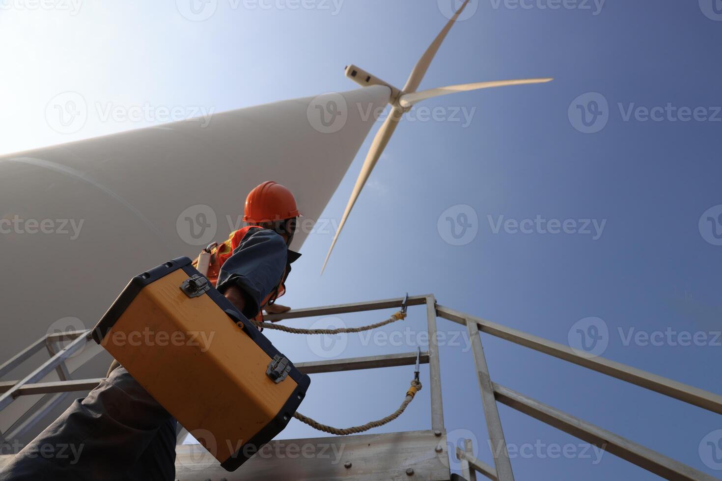 Specialist wind turbine technician working at the base of the turbine. Wind turbine service technician wearing safety uniform and safety harness working at windmill farm photo