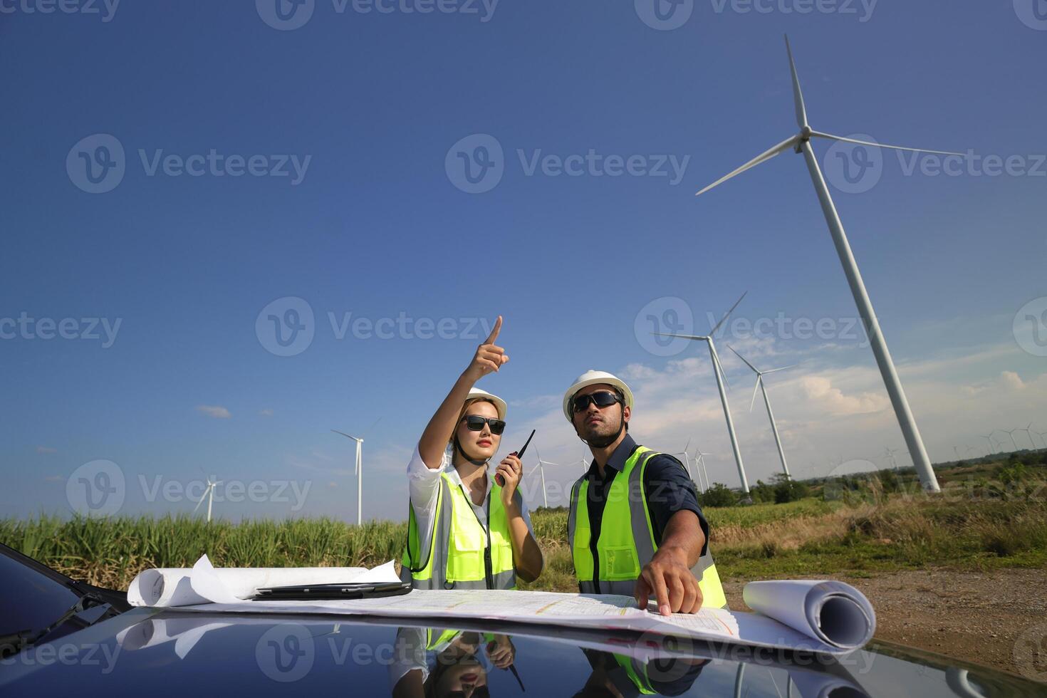 Wind turbine engineers working on the roof of car at a wind turbine field, checking and comparing the blueprint and condition of the Turbine's Electrical Power photo