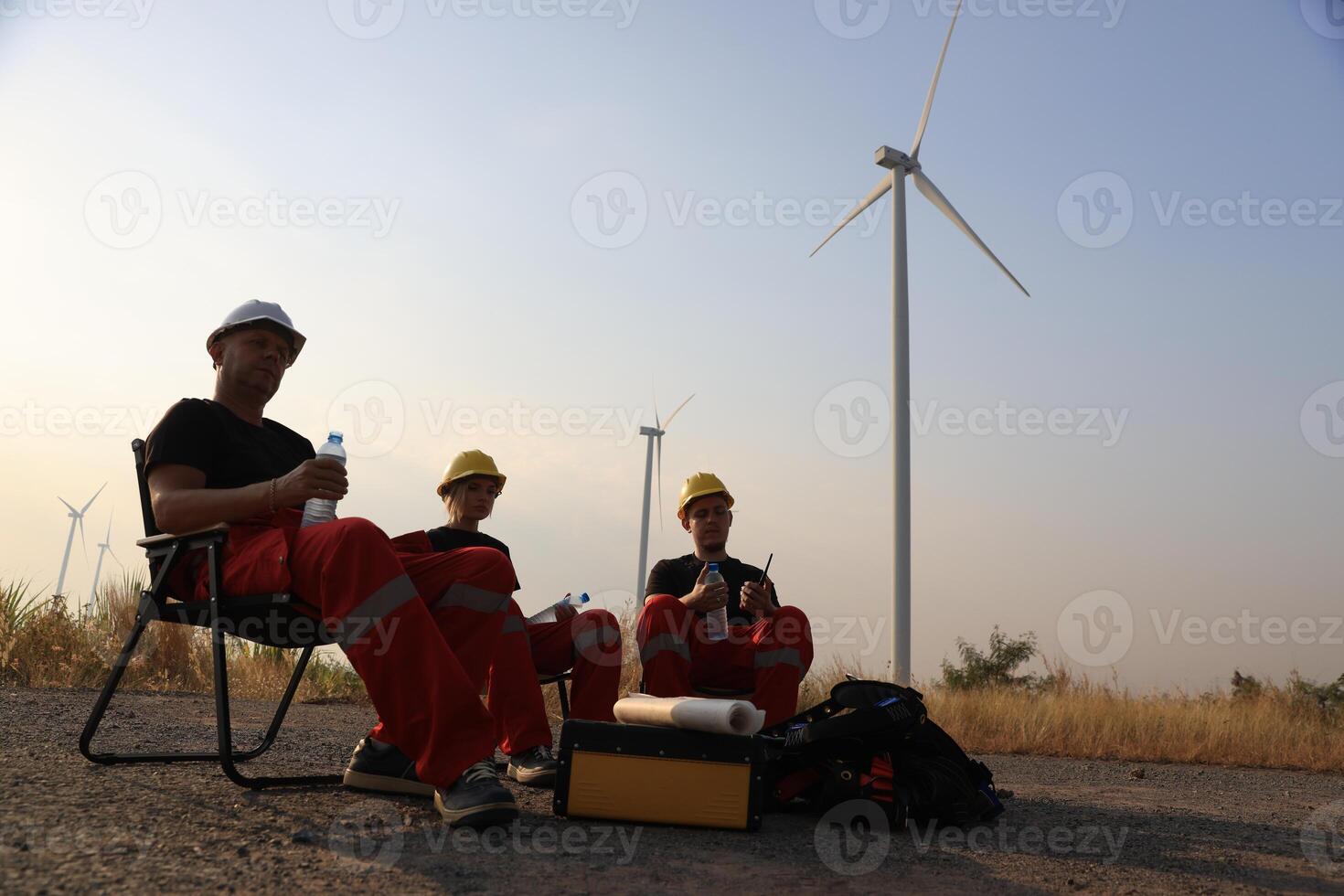 Portrait Windmill engineer team with red work uniform with safety hard hat and harness work in wind turbine farm photo
