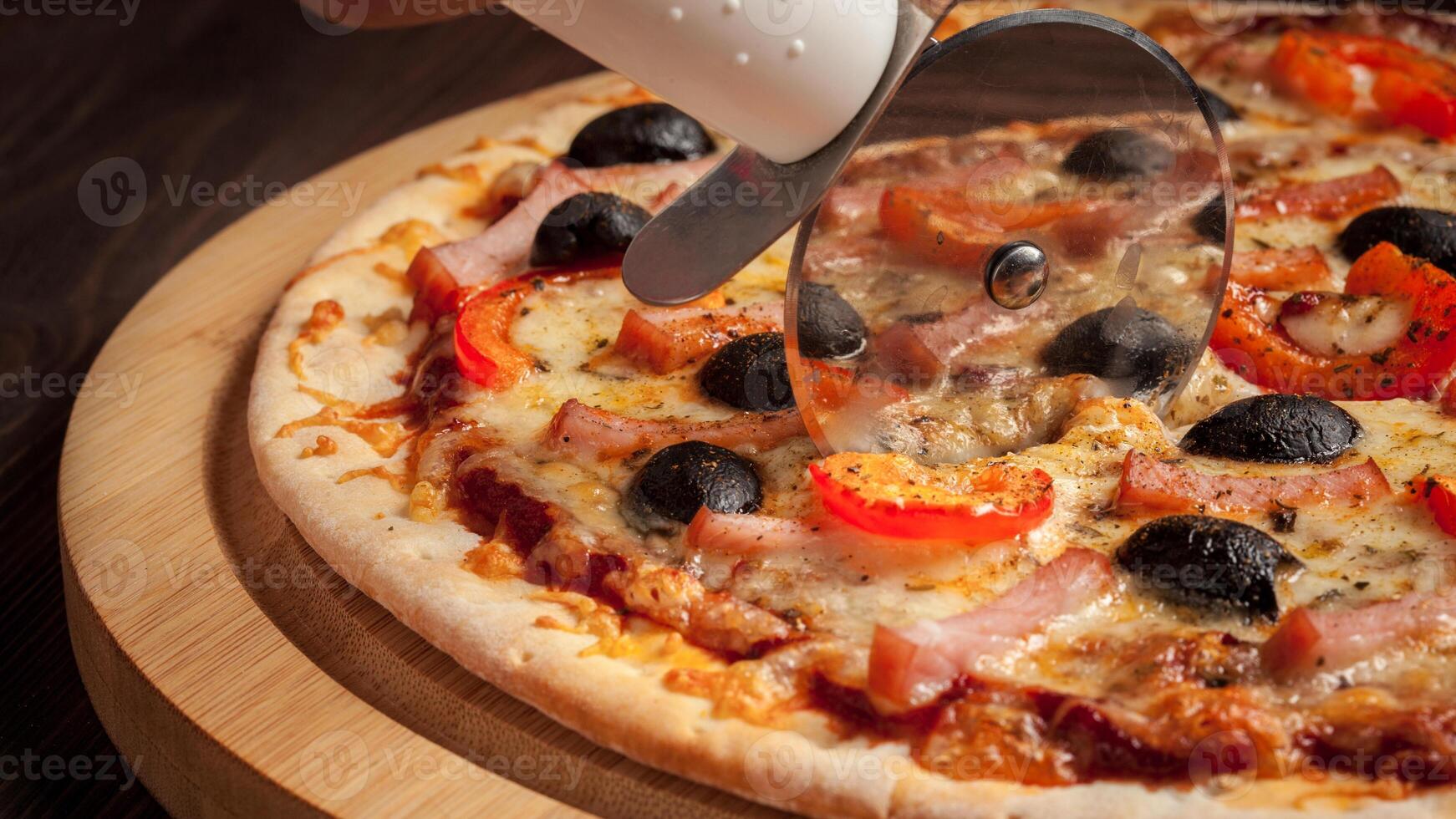 Pizza cutter wheel slicing ham pizza photo