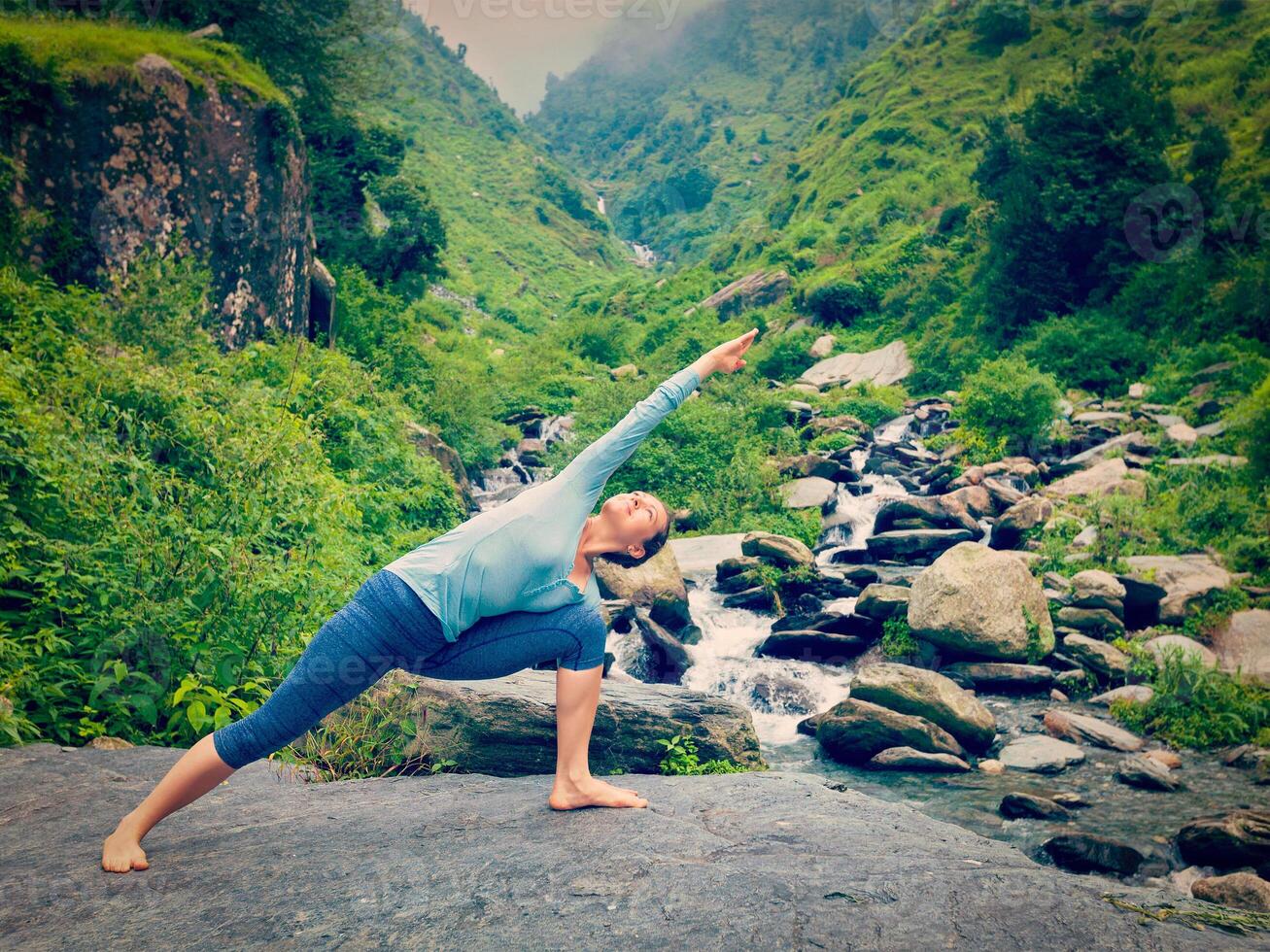 Woman practices yoga asana Utthita Parsvakonasana outdoors photo