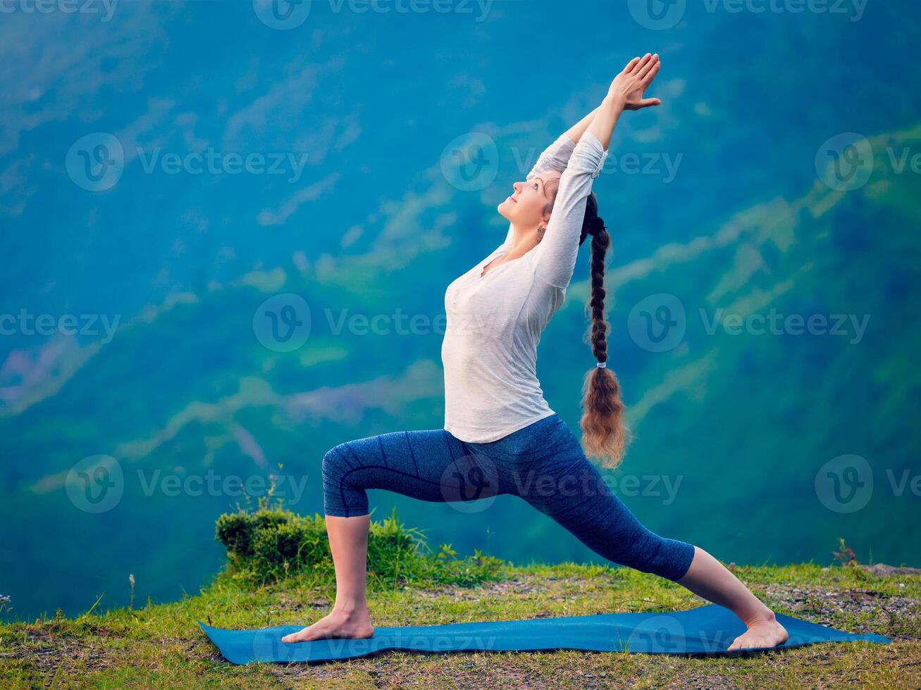 Woman doing yoga asana Virabhadrasana 1 - Warrior pose outdoors photo