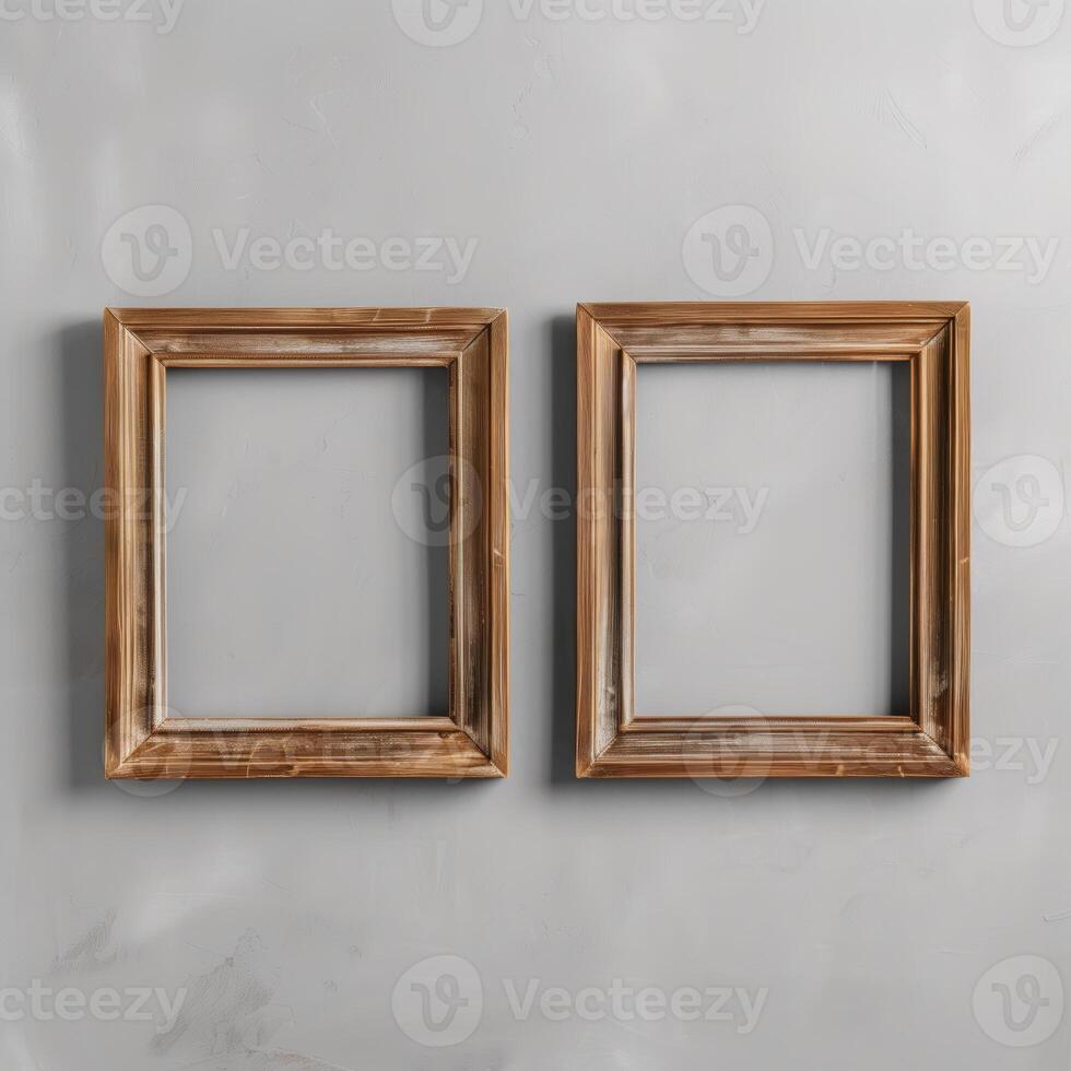 Two empty, wide, wooden frames on a light gray plain wall. photo
