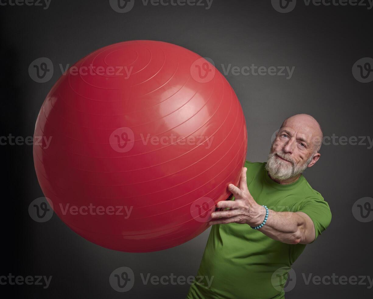 senior man exercising with a large Swiss ball photo