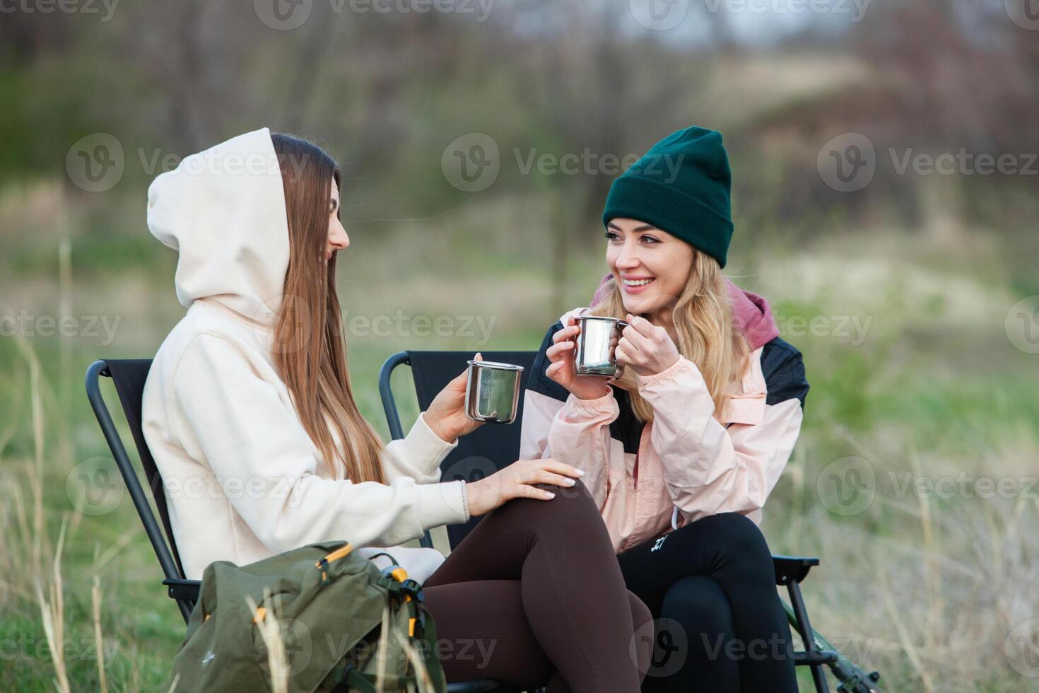 Two young women hiking in the mountains and drinking tea from a kettle. Travel, traveler. photo