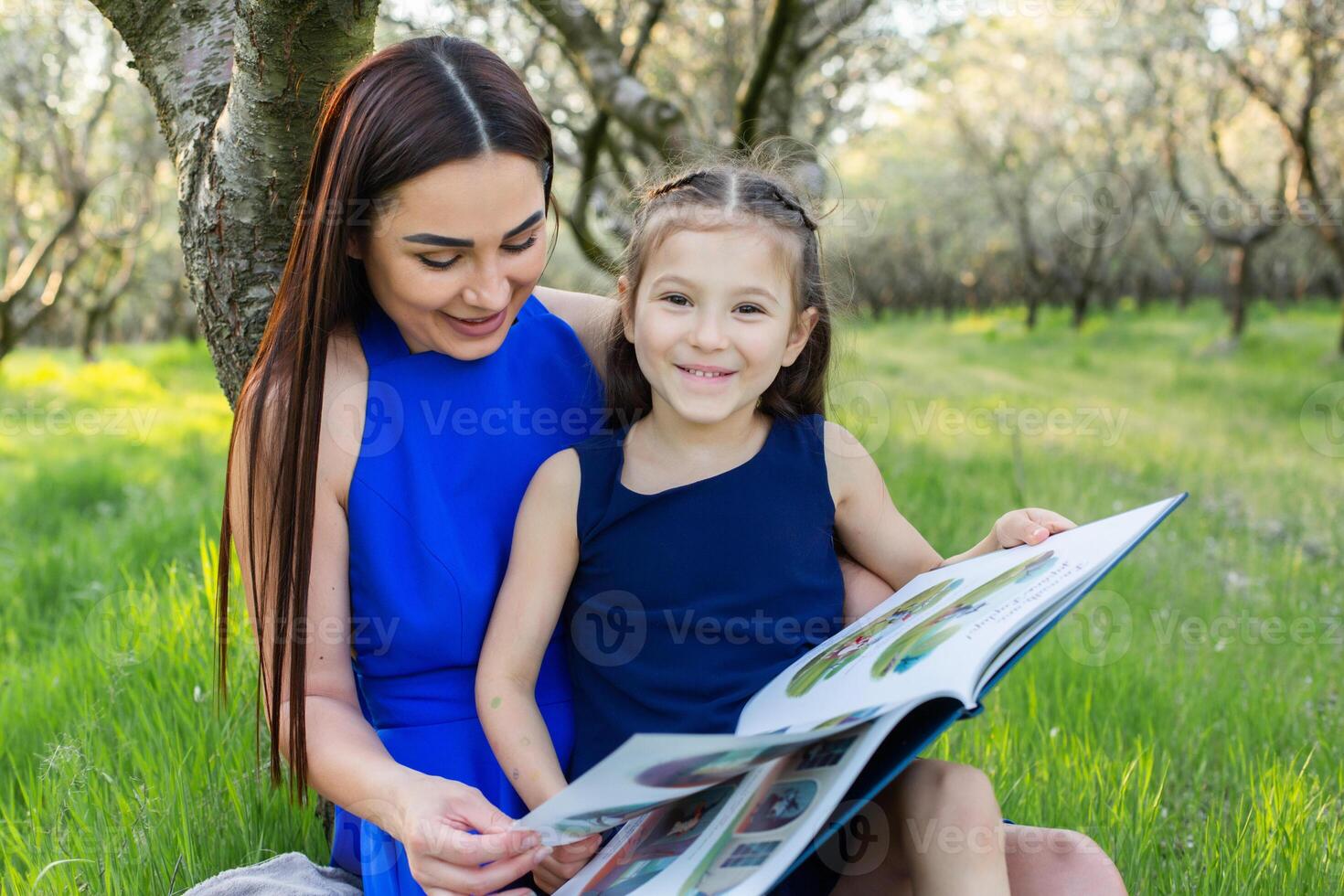mother and daughter are reading together in the park photo