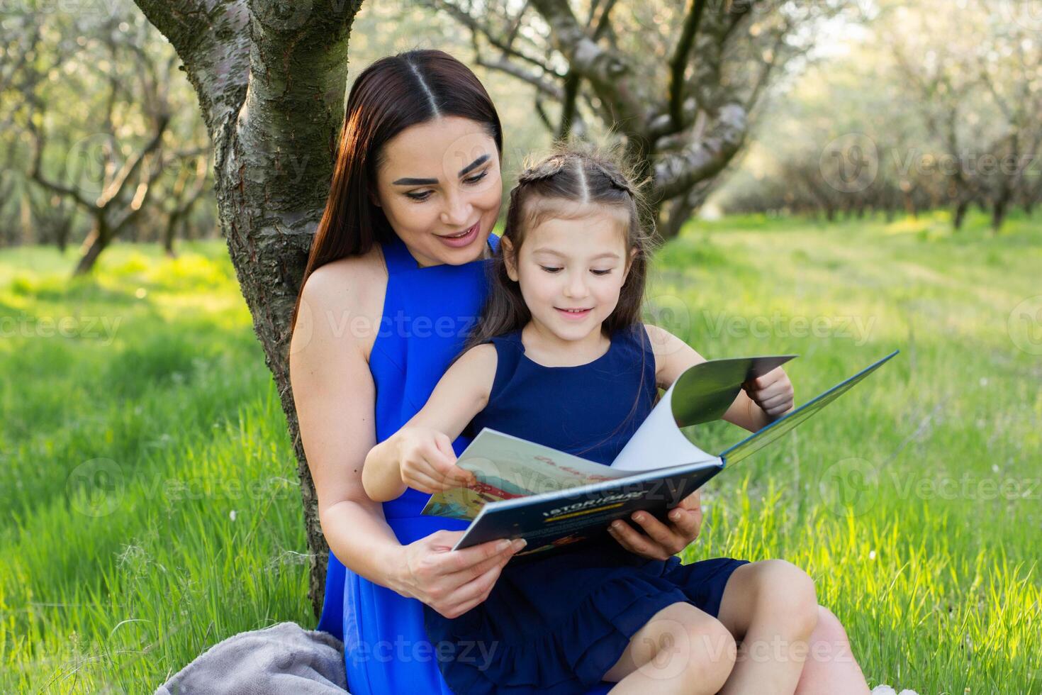 mother and daughter are reading together in the park photo