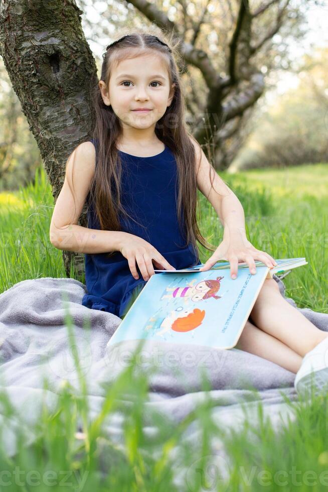 a child girl is reading a book in the park photo