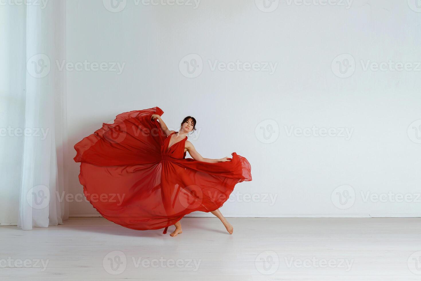 bailarín en un rojo volador vestido. mujer bailarina bailando en un blanco estudio antecedentes foto