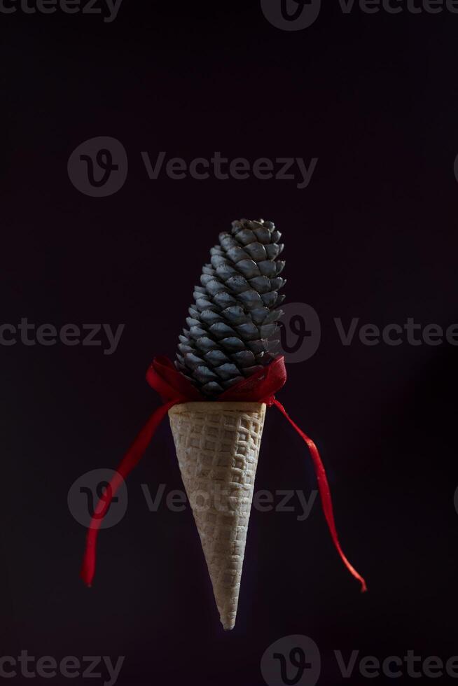 A cone of ice cream is suspended in the air with a red ribbon photo
