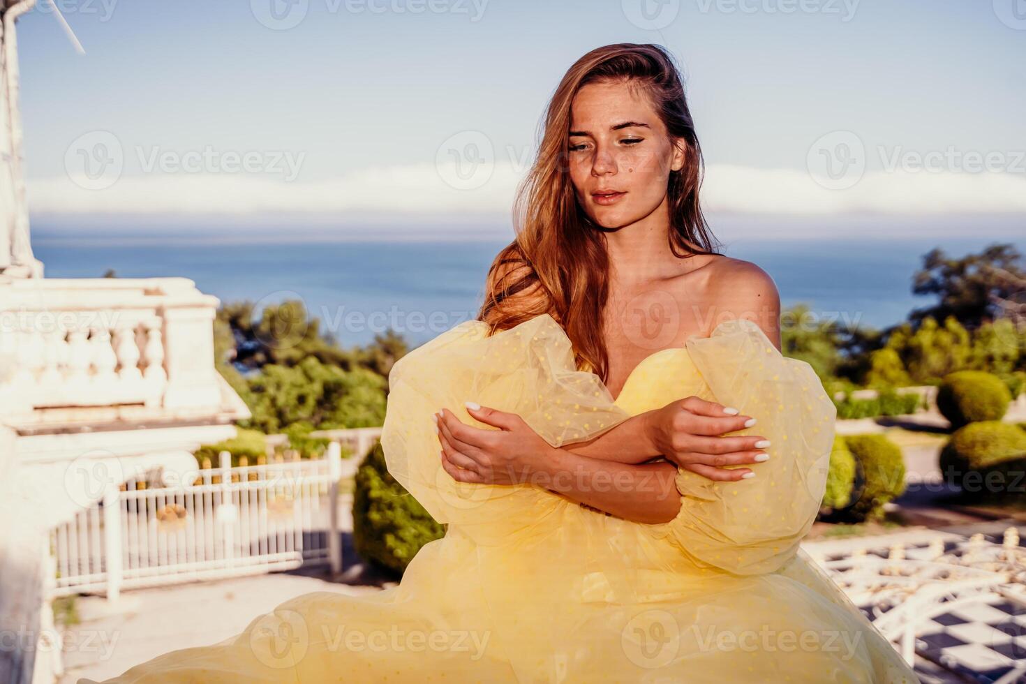 Woman yellow sea dress. Portrait of a beautiful young woman with brown hair in a gorgeous yellow dress looks into the distance. photo
