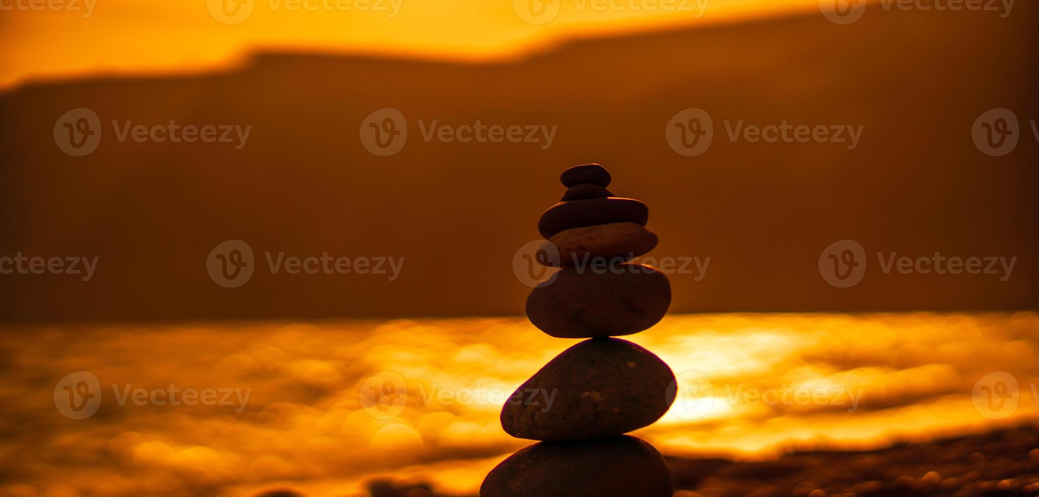 Pebble pyramid silhouette on the beach. Sunset with sea in the background. Zen stones on the sea beach concept, tranquility, balance. Selective focus photo