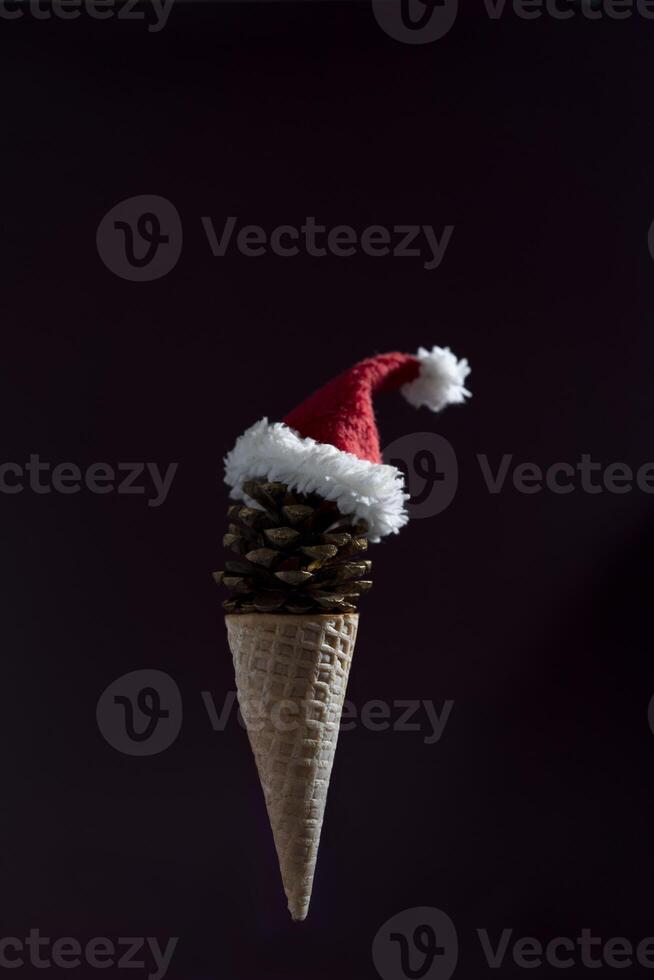 A cone shaped ice cream cone with a red hat on top. The cone is made of pine cones and the hat is made of white and red fabric. photo