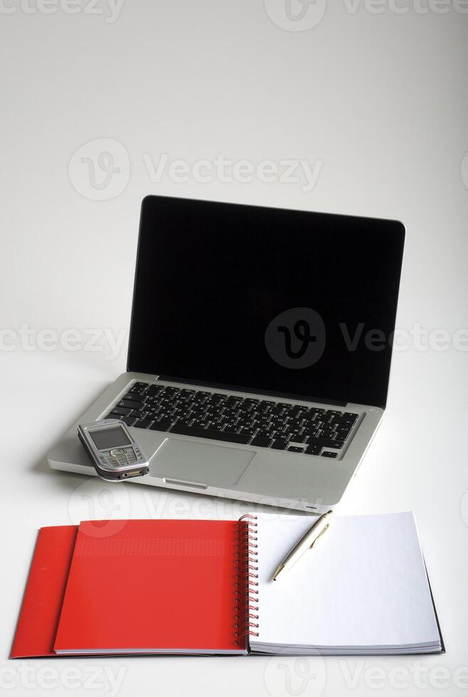 Phone, laptop and empty notebook on the desk photo