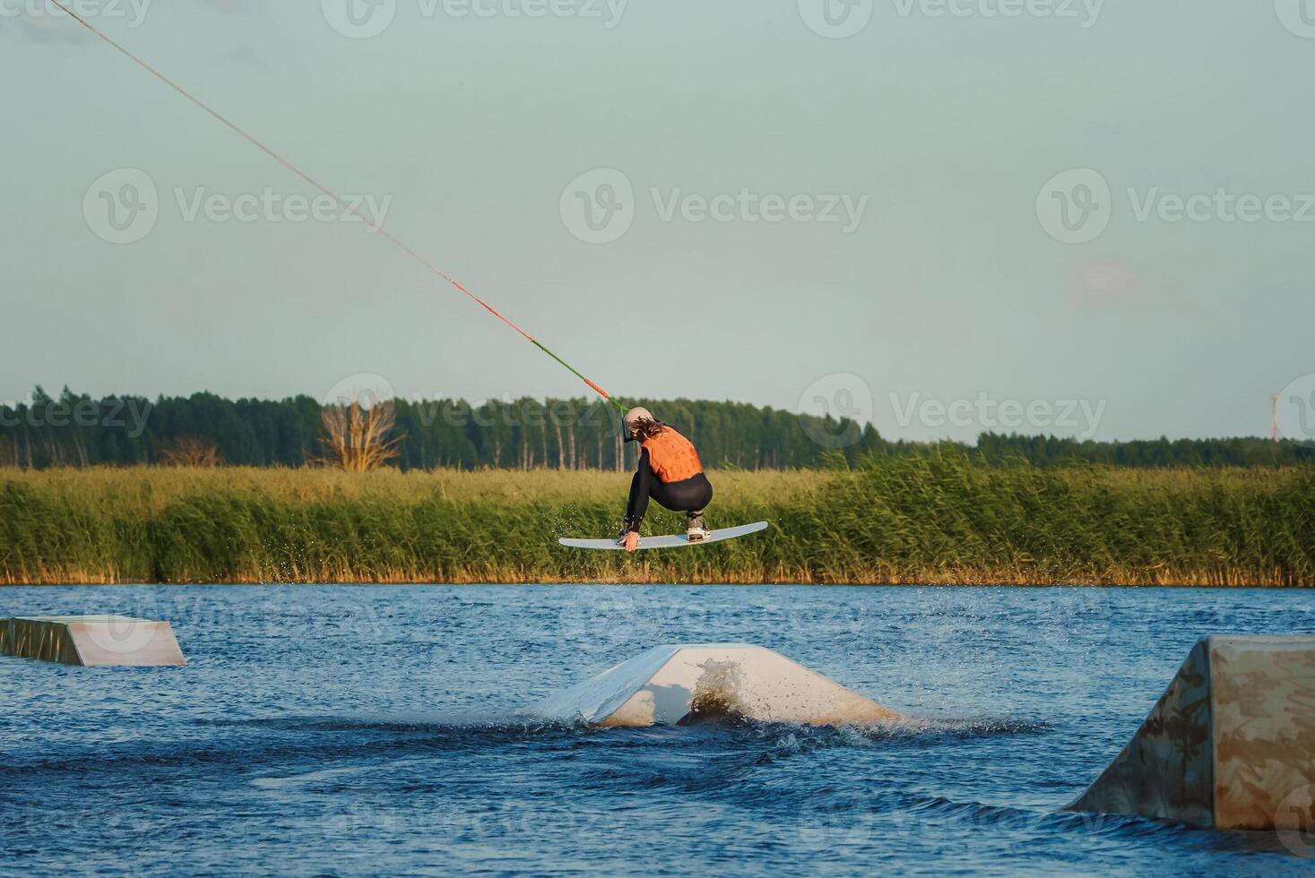 Wake boarding female sportsman girl jumping high wake boarding raley trick with huge water splash in the cable park photo