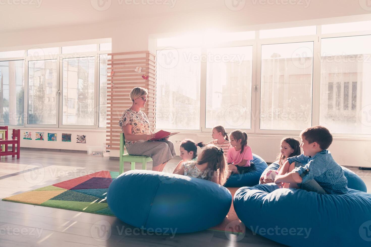Reading time in elementary school or kindergarten, teacher reading a book to kids in elementary school or kindergaden. Selective focus photo