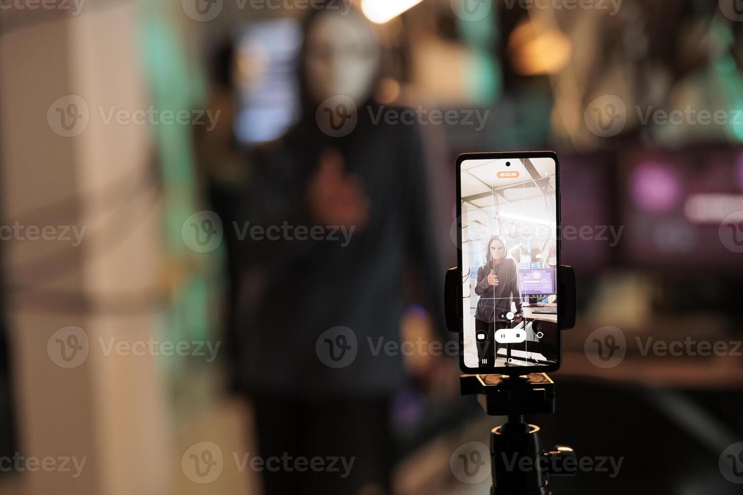 Masked hacker broadcasting live video to ask for ransom, hacking computer system password and breaking into online server. Anonymous thief attacking database and stealing information. photo