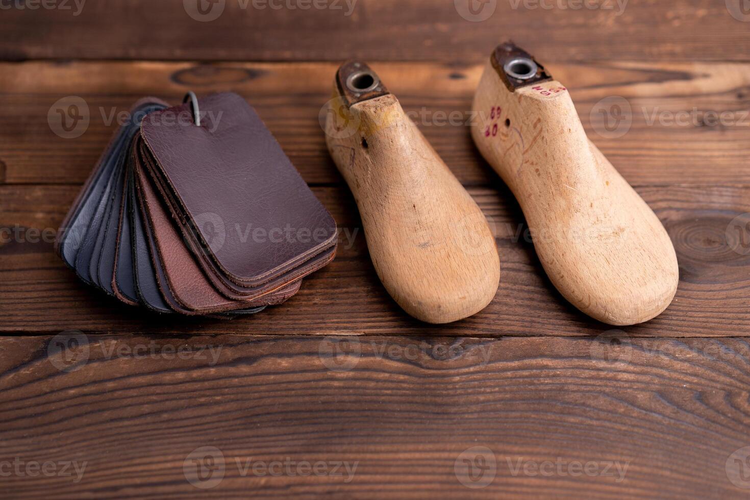 Leather samples for shoes and wooden shoe last on dark wooden table. photo