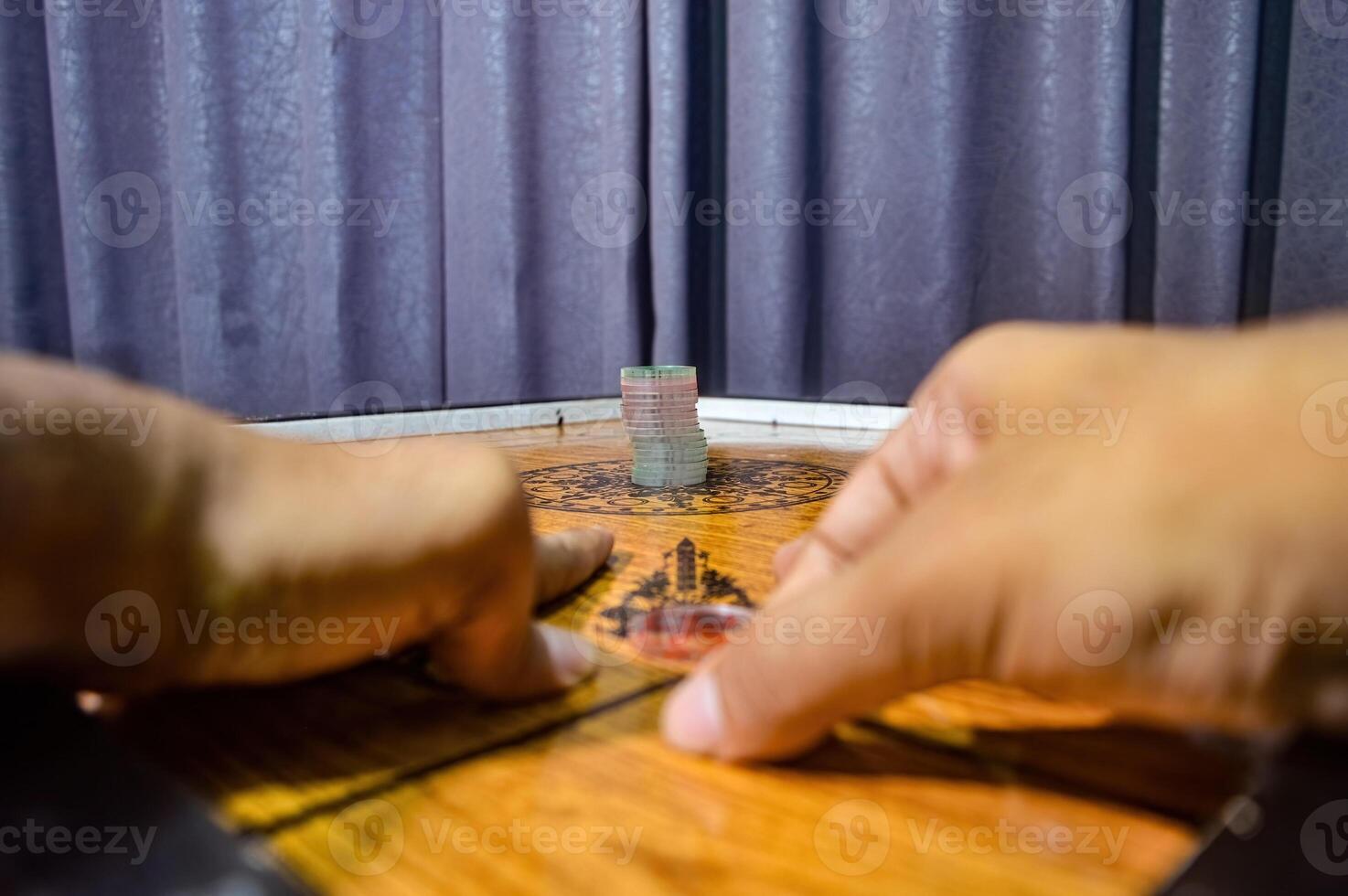 hands playing a traditional game called carom photo