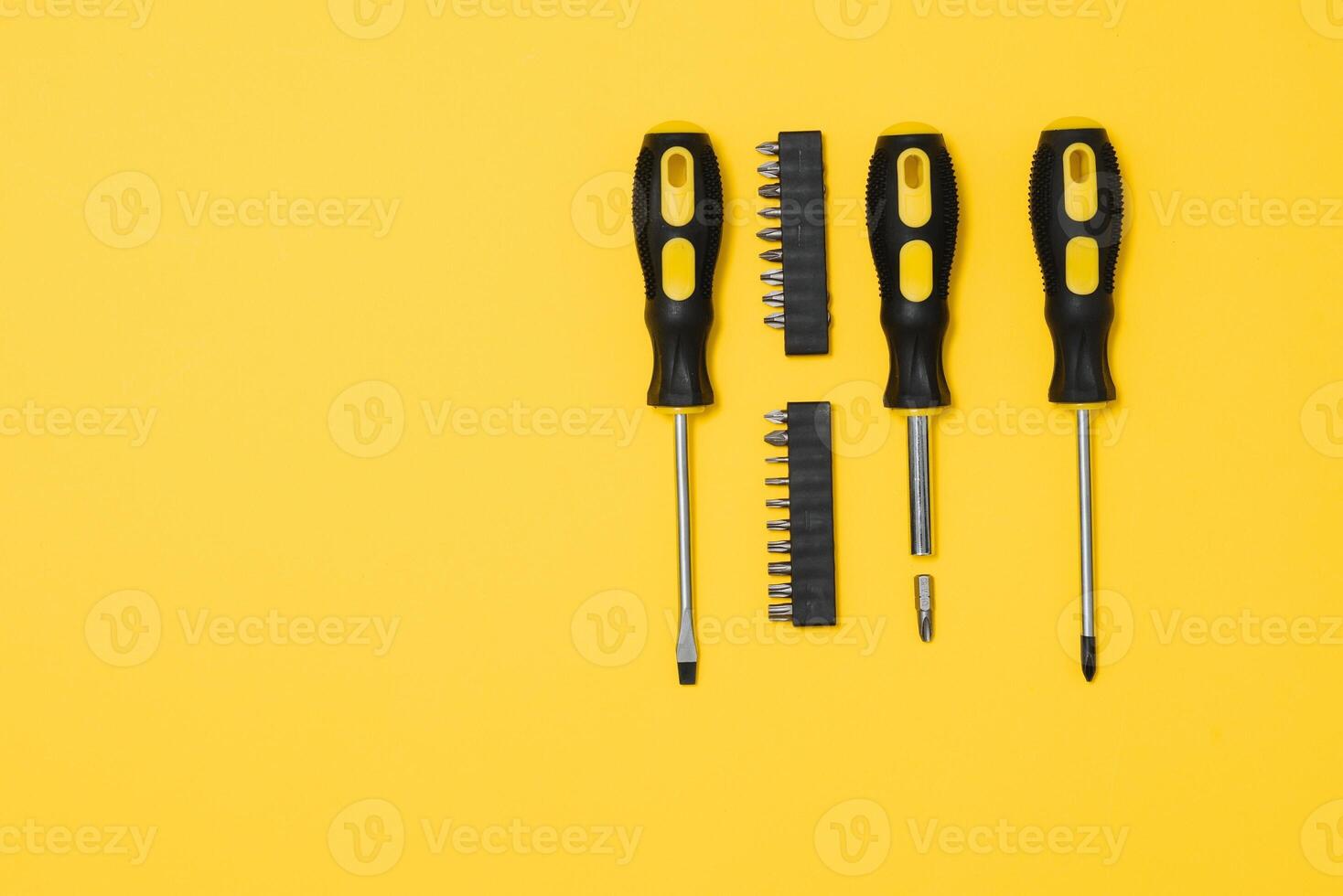 three black and yellow screwdrivers on a yellow background with space for text. Tools, construction and workshop, home repairs, slusar work photo