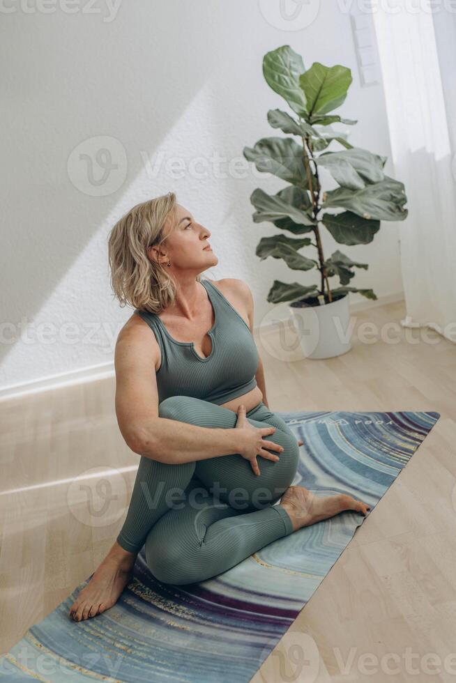 A 50-year-old woman does yoga at home photo