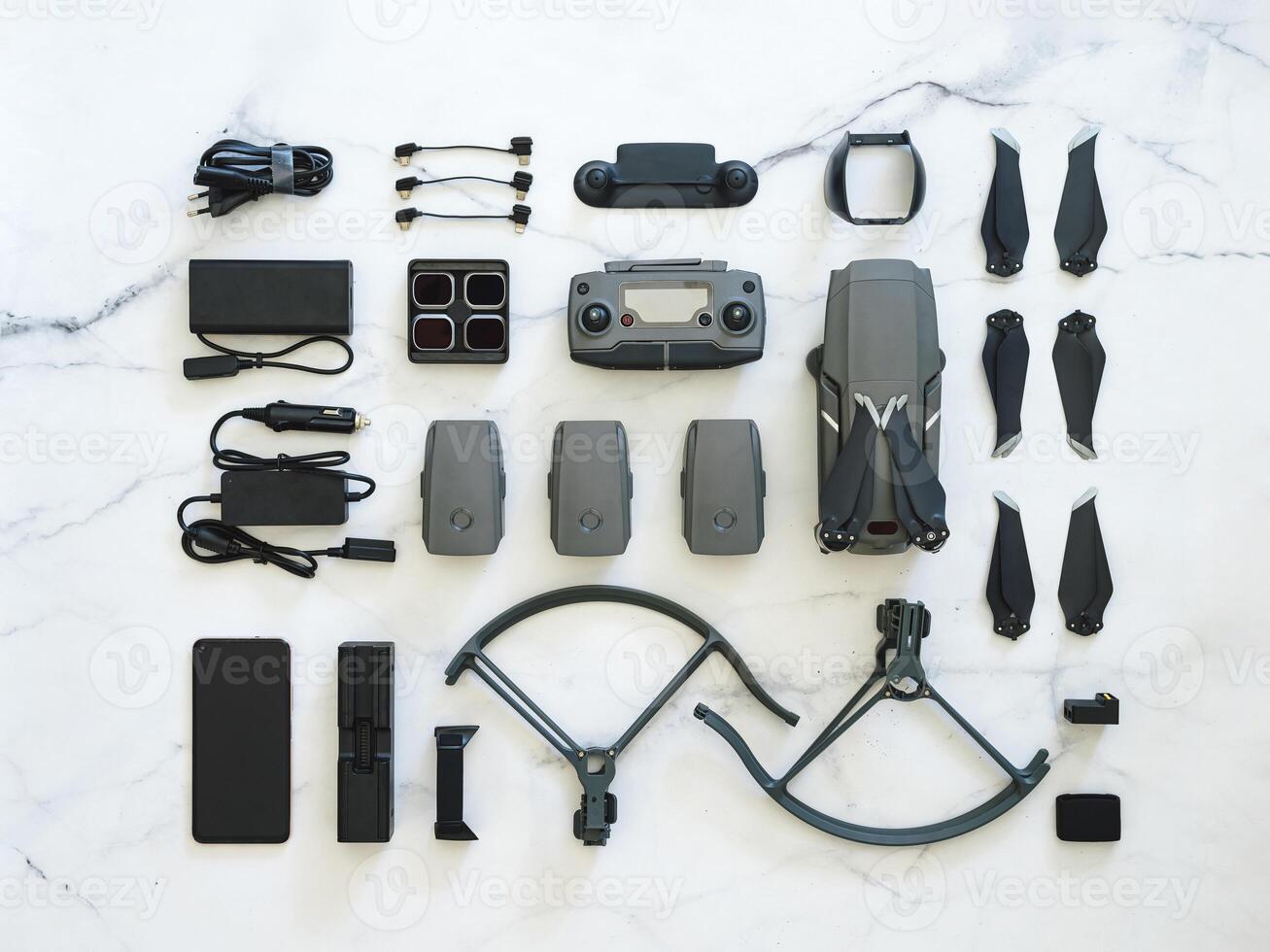 Set of folding drone or quadcopter with many accessories, top view or flat lay. Kit of folding drone and equipment for UAV over white marble background. Creative layout photo
