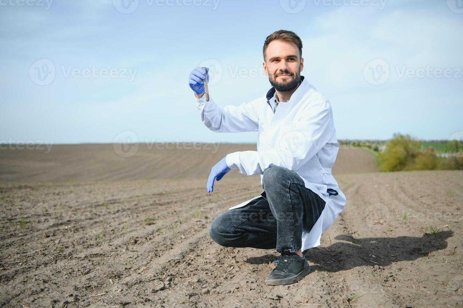 Agronomist studying samples of soil in field photo
