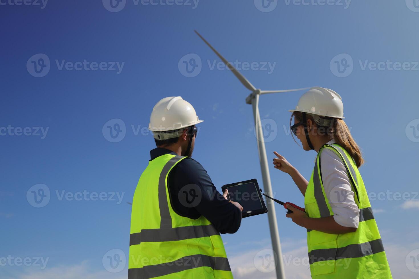 Wind turbine engineers working on the roof of car at a wind turbine field, checking and comparing the blueprint and condition of the Turbine's Electrical Power photo