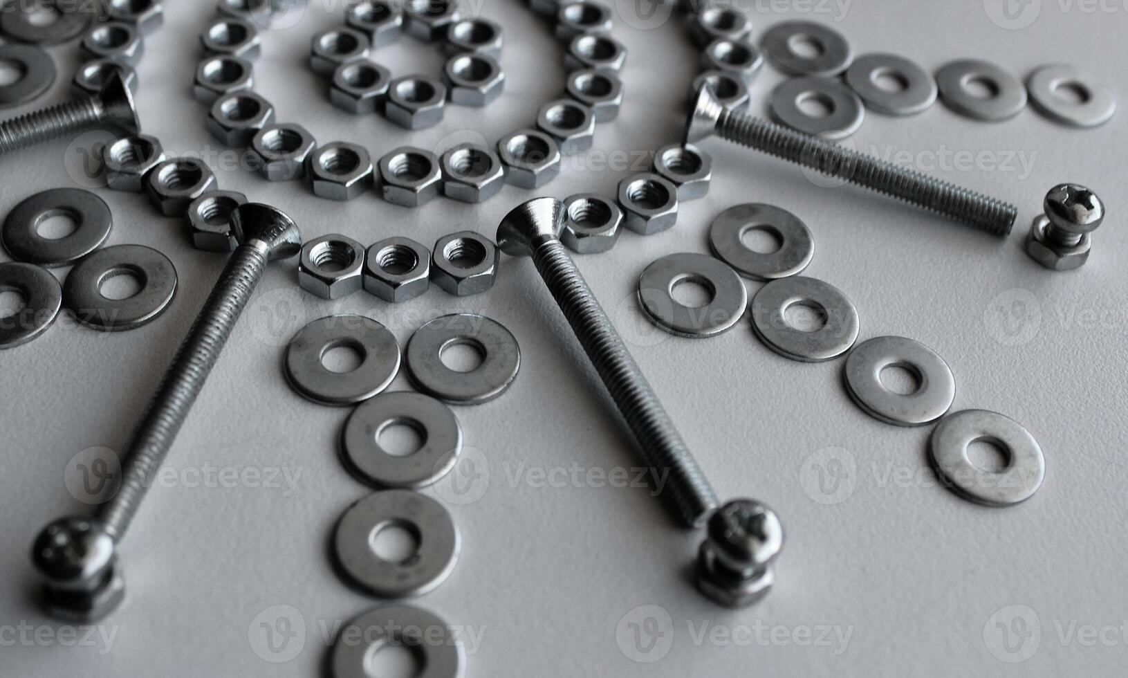 Part Of Design Pattern Of Steel Fasteners And Bolts In Star Shape On White Surface photo