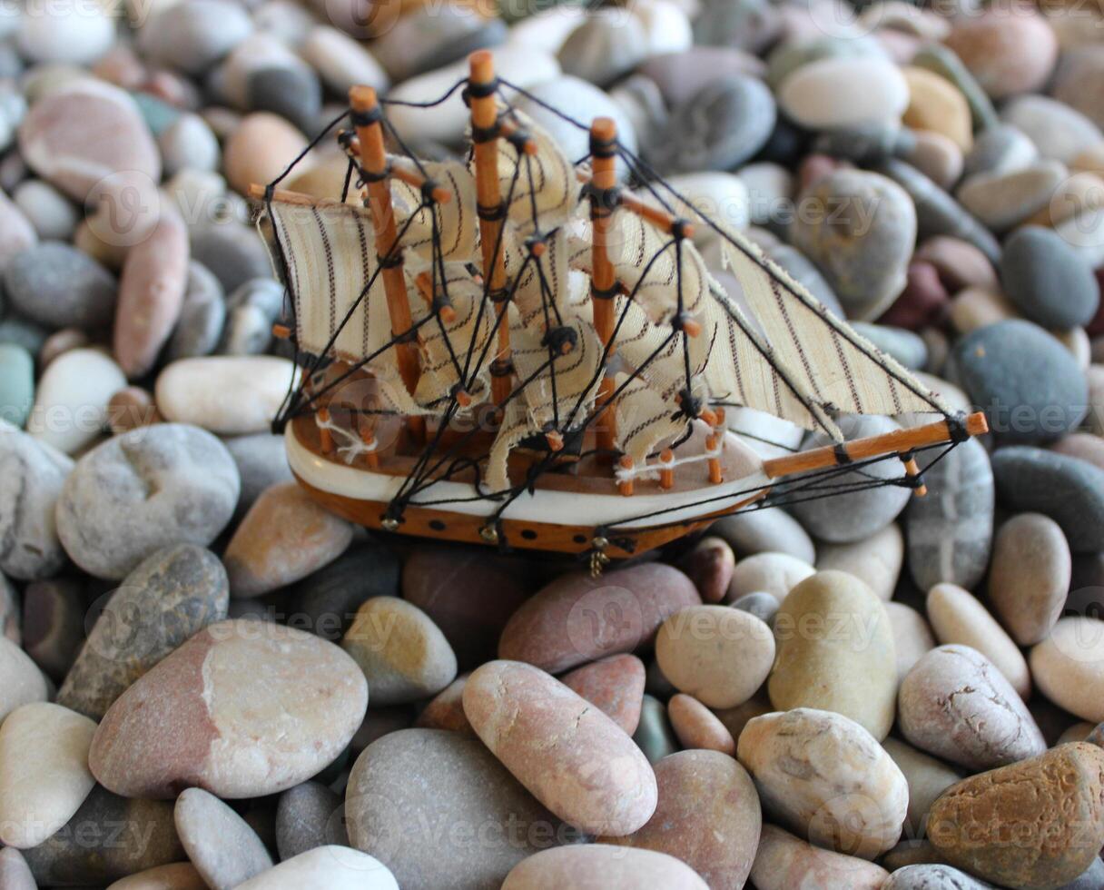 Miniature Of Sail Ship Over Small Sea Stones. Beached Ship Concept Stock Photo With Soft Focus