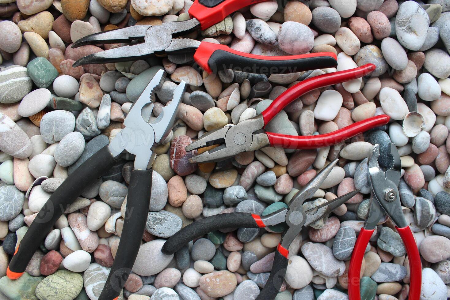 Concept Photo With Set Of Different Types Of Mechanics Pliers On Smooth Rocks Top View