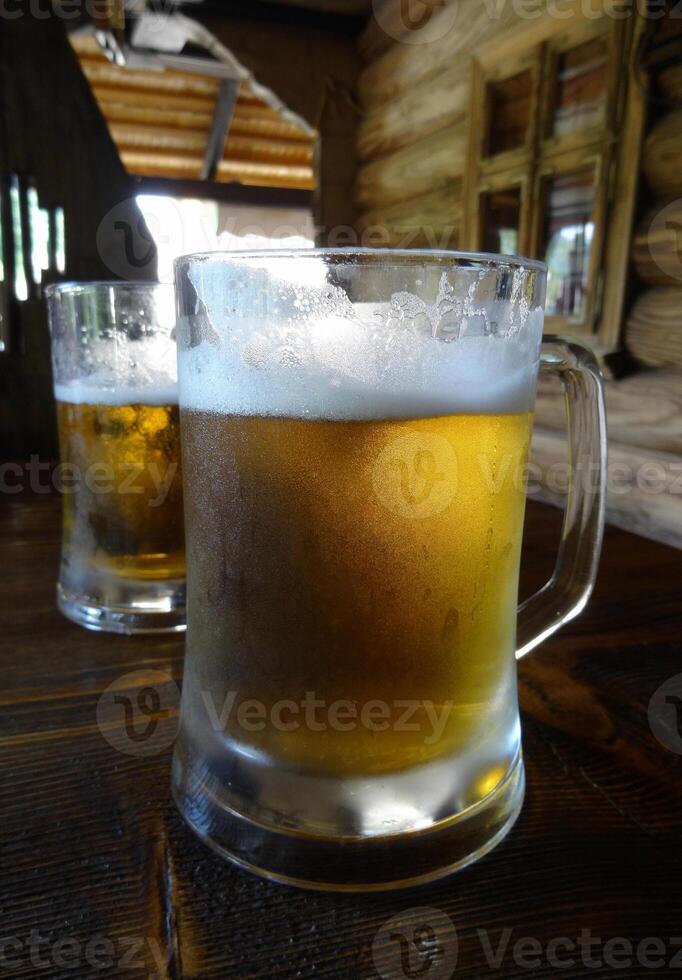Two full glasses of light beer on the table at pub in country style photo