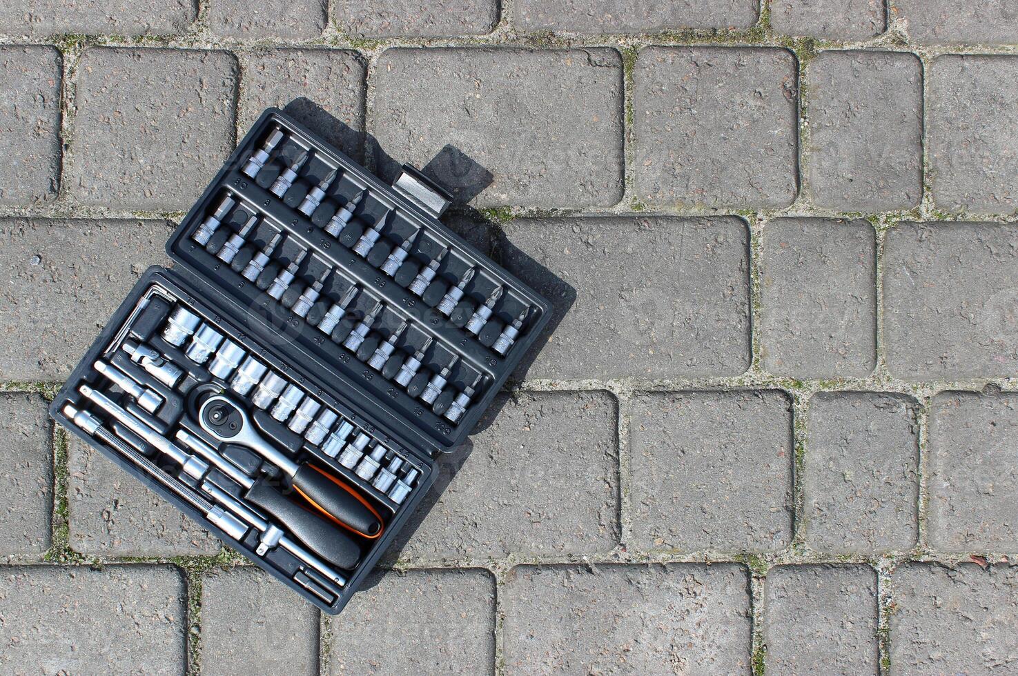 A set of repairing tools in a plastic case on a concrete paving slabs photo