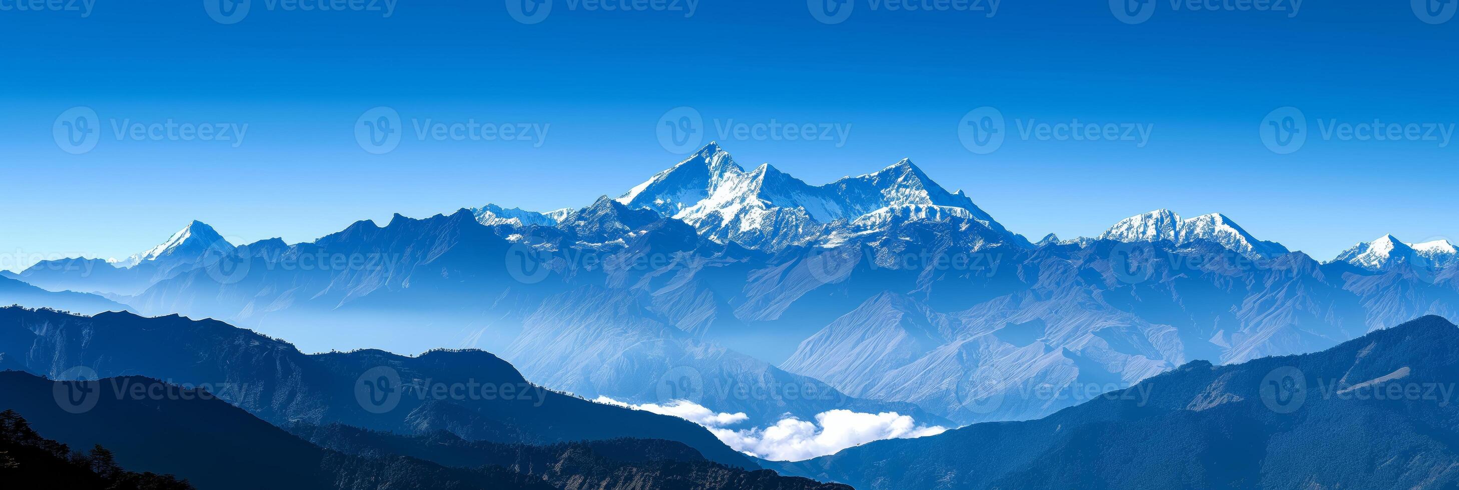 Mountain range with snow, clouds, and electric blue sky in background photo