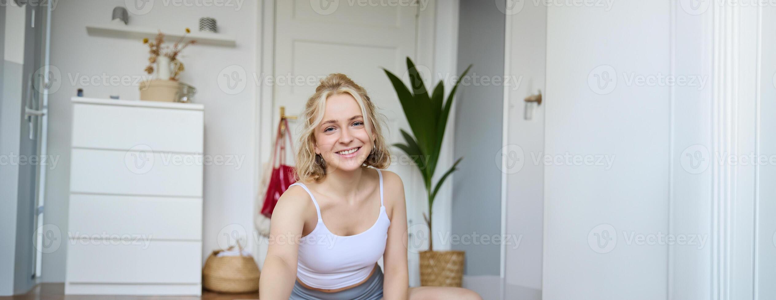 Vertical shot of athletic, fitness woman recording of herself on digital camera, creating content for social media about workout and home exercises photo