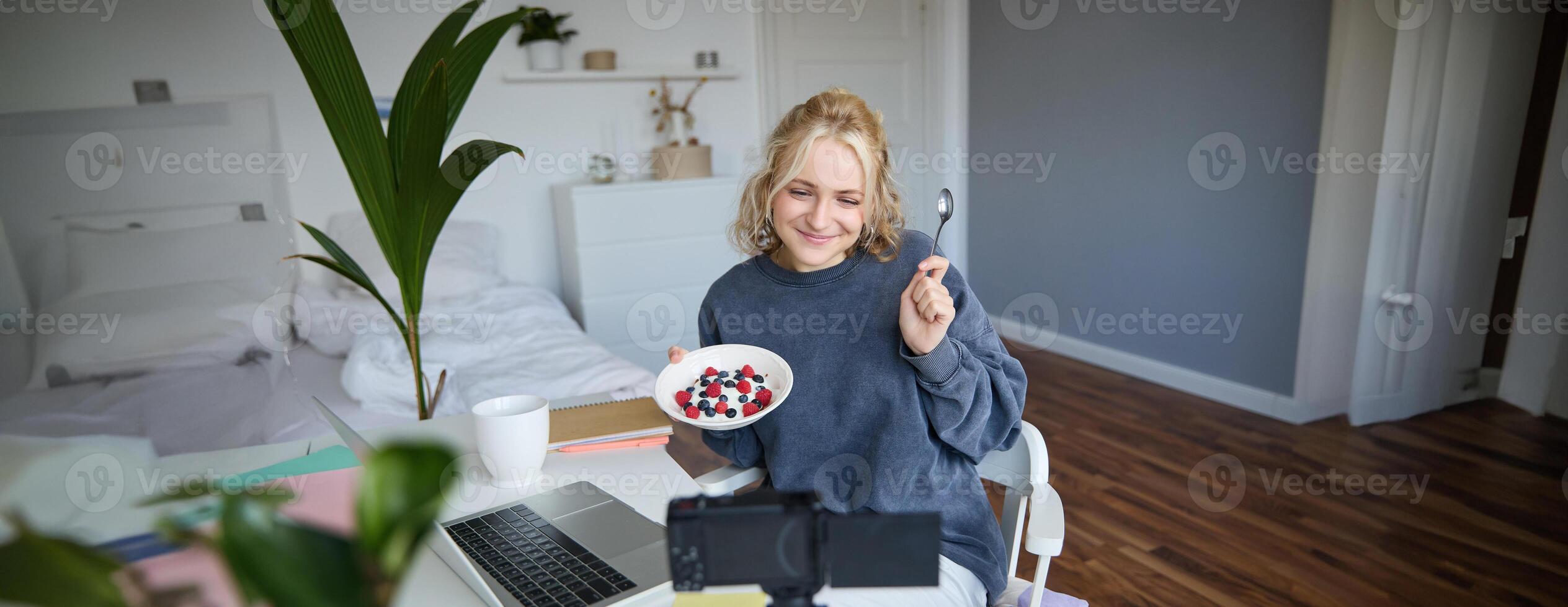 Portrait of young woman vlogger, recording herself while eating homemade healthy breakfast, creating vlog content for followers photo