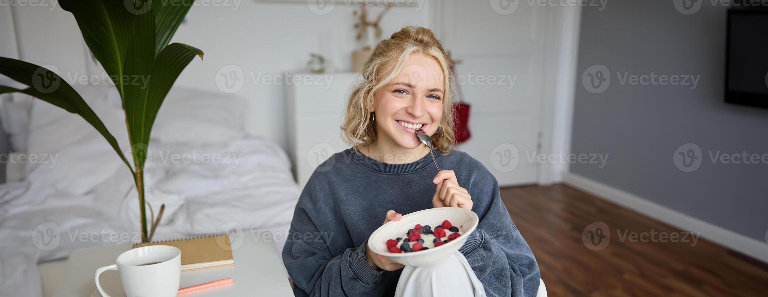 Portrait of young vlogger, content creator, showing her homemade breakfast on camera, eating dessert, smiling and looking happy photo