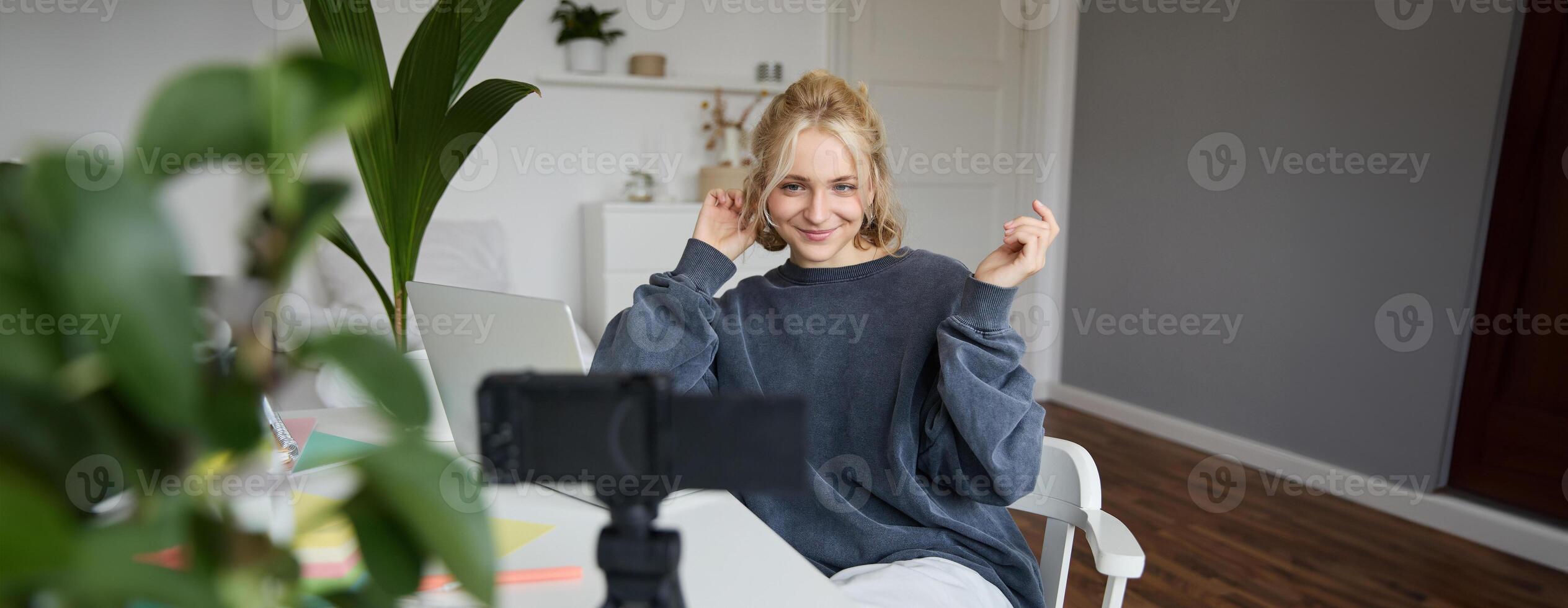 Portrait of young woman, lifestyle blogger, recording vlog about her life and daily routine, sitting in front of laptop, talking to followers, sitting in her room photo