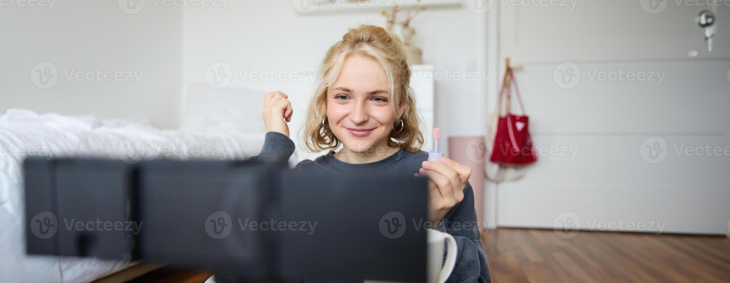 Image of happy, beautiful young social media influencer, female vlogger records a on digital camera, tutorial on how to put makeup, getting ready for going out, talking to followers photo