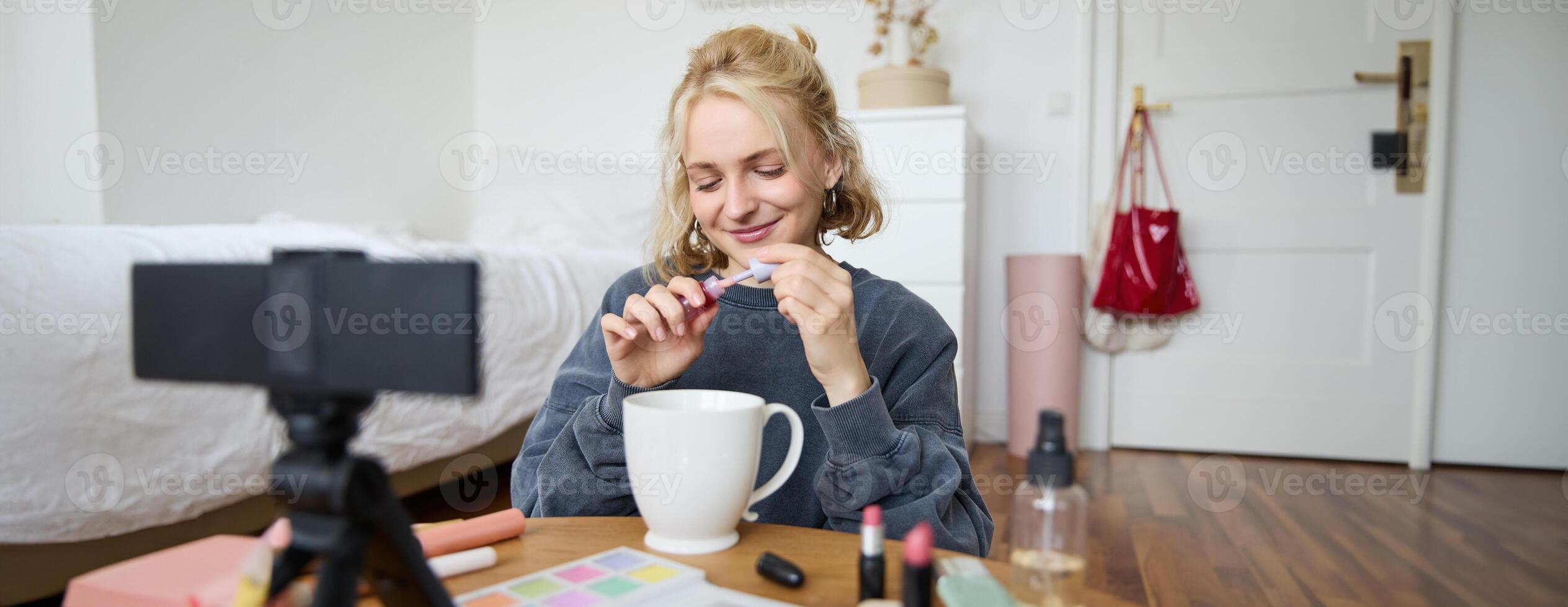 Image of happy, beautiful young social media influencer, female vlogger records a on digital camera, tutorial on how to put makeup, getting ready for going out, talking to followers photo
