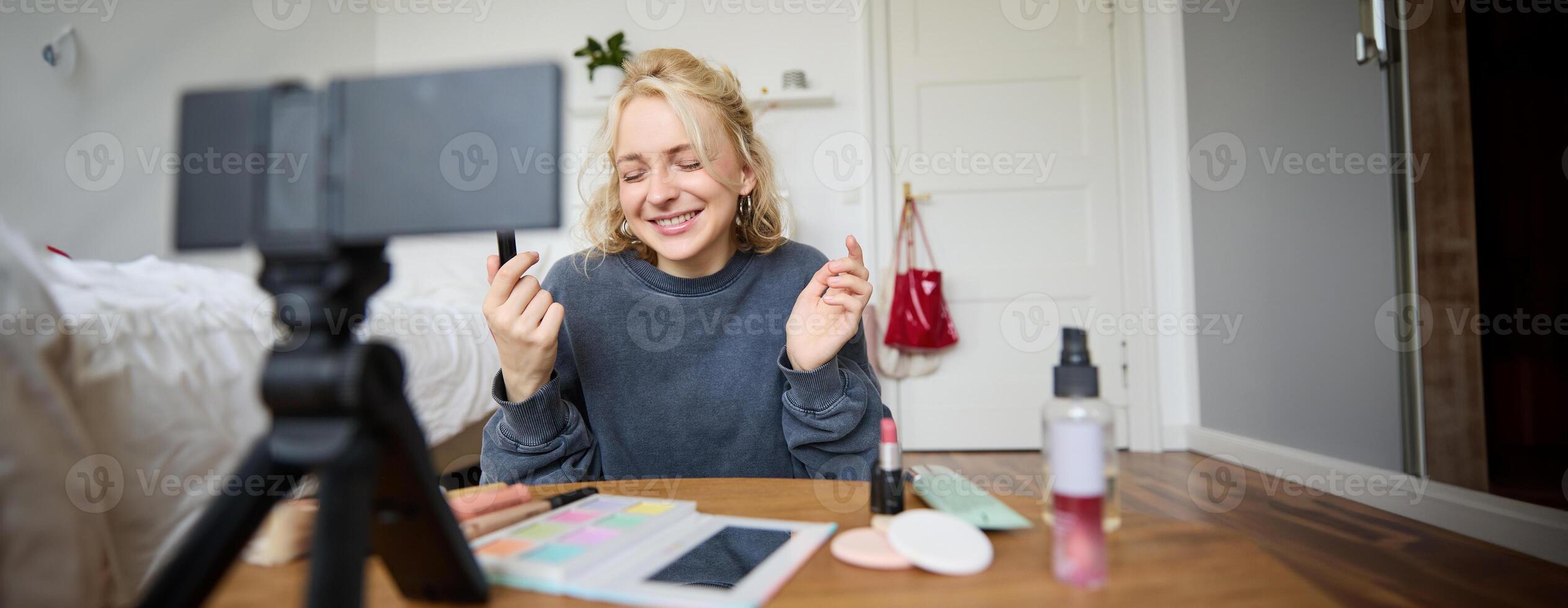 Portrait of young content maker, woman blogger recording a on digital camera, showing lipstick colour to her followers, creating lifestyle vlog for social media account photo