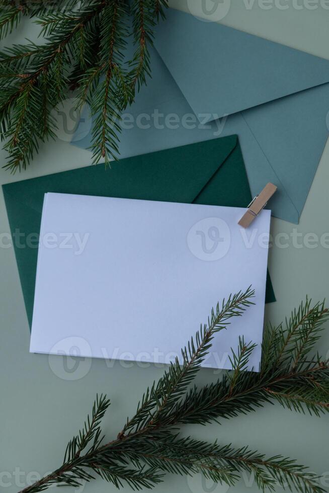 Empty paper letter envelope note Copy space Christmas mockup for lettering art drawing with fir branches on pastel green background. Letter to Santa Claus concept. Flat lay, top view photo