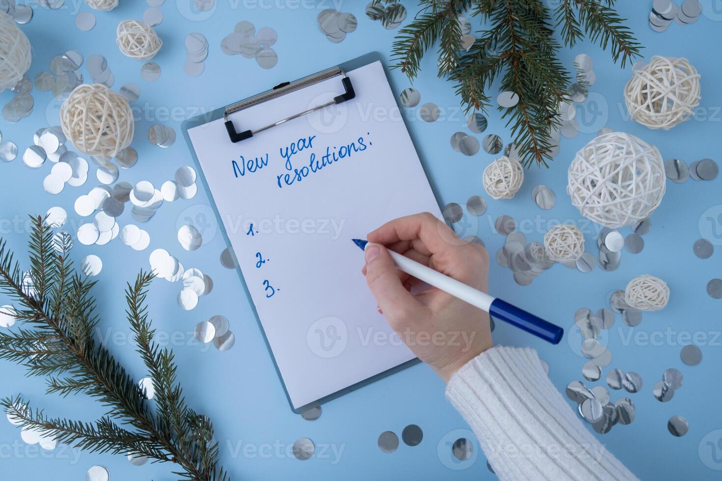 Female hands writing handwritten new year resolutions aims goals on paper notepad. Preparation for New Year. Concept of planning and setting goals for personal development photo