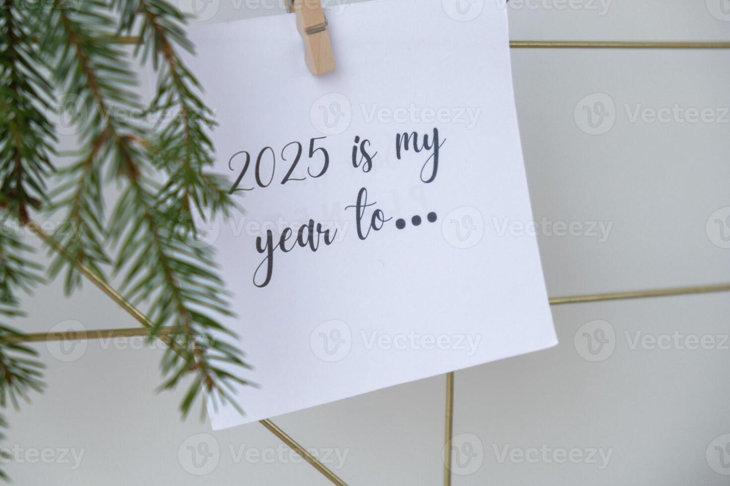 2025 IS MY YEAR TO text on white paper note on vision board with Christmas decor. New year aims resolutions. New me you concept visualizing dreams photo