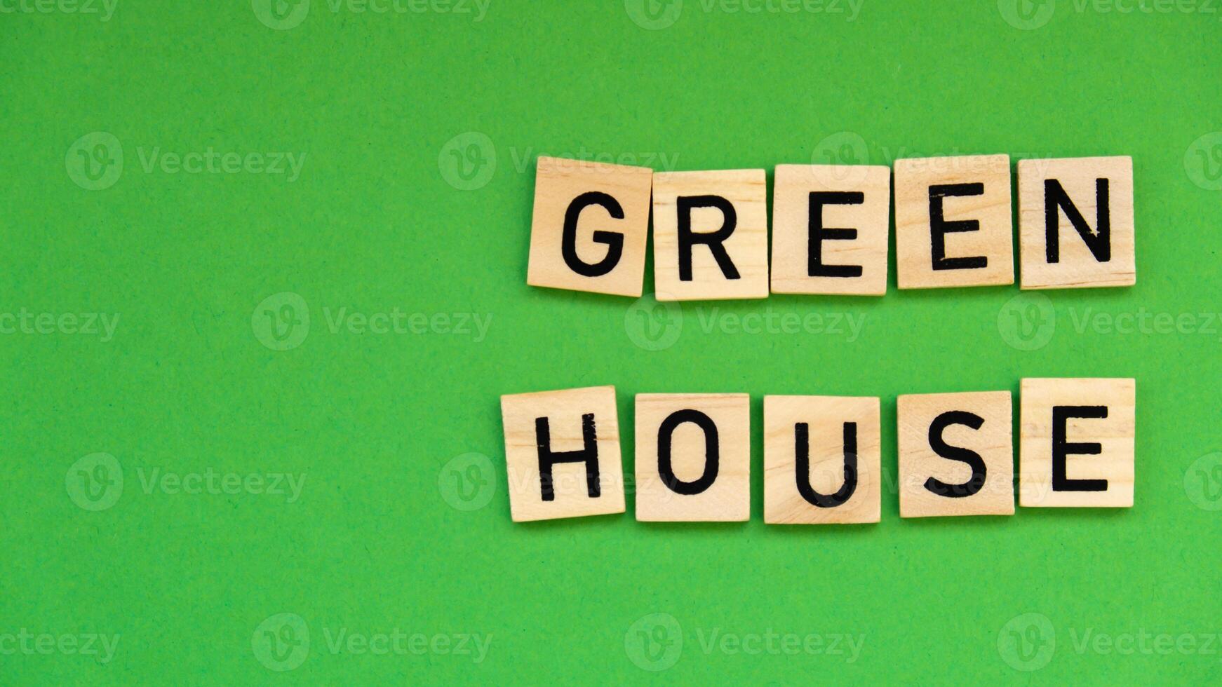Green house text on wooden blocks on green background. Ecological concept Sustainable responsible living. Copy space. Single word photo