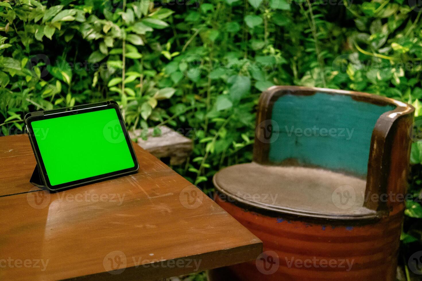 Green Screen iPad or Tablet on Wooden Table with Green Plants Background photo