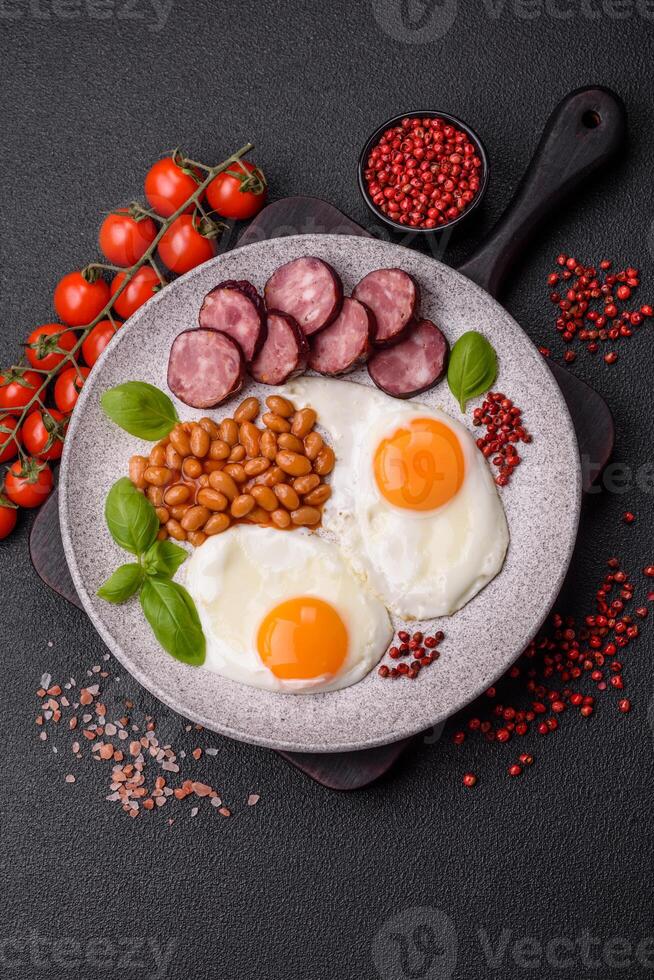 English breakfast with fried eggs, bacon, beans, tomatoes, spices and herbs photo