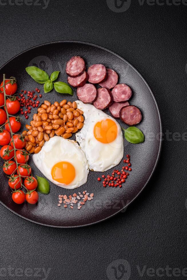 English breakfast with fried eggs, bacon, beans, tomatoes, spices and herbs photo