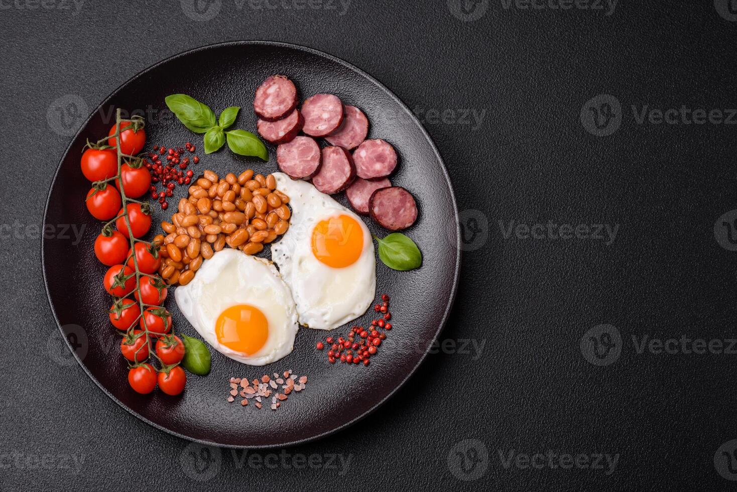 English breakfast with fried eggs, bacon, beans, tomatoes, spices and herbs photo